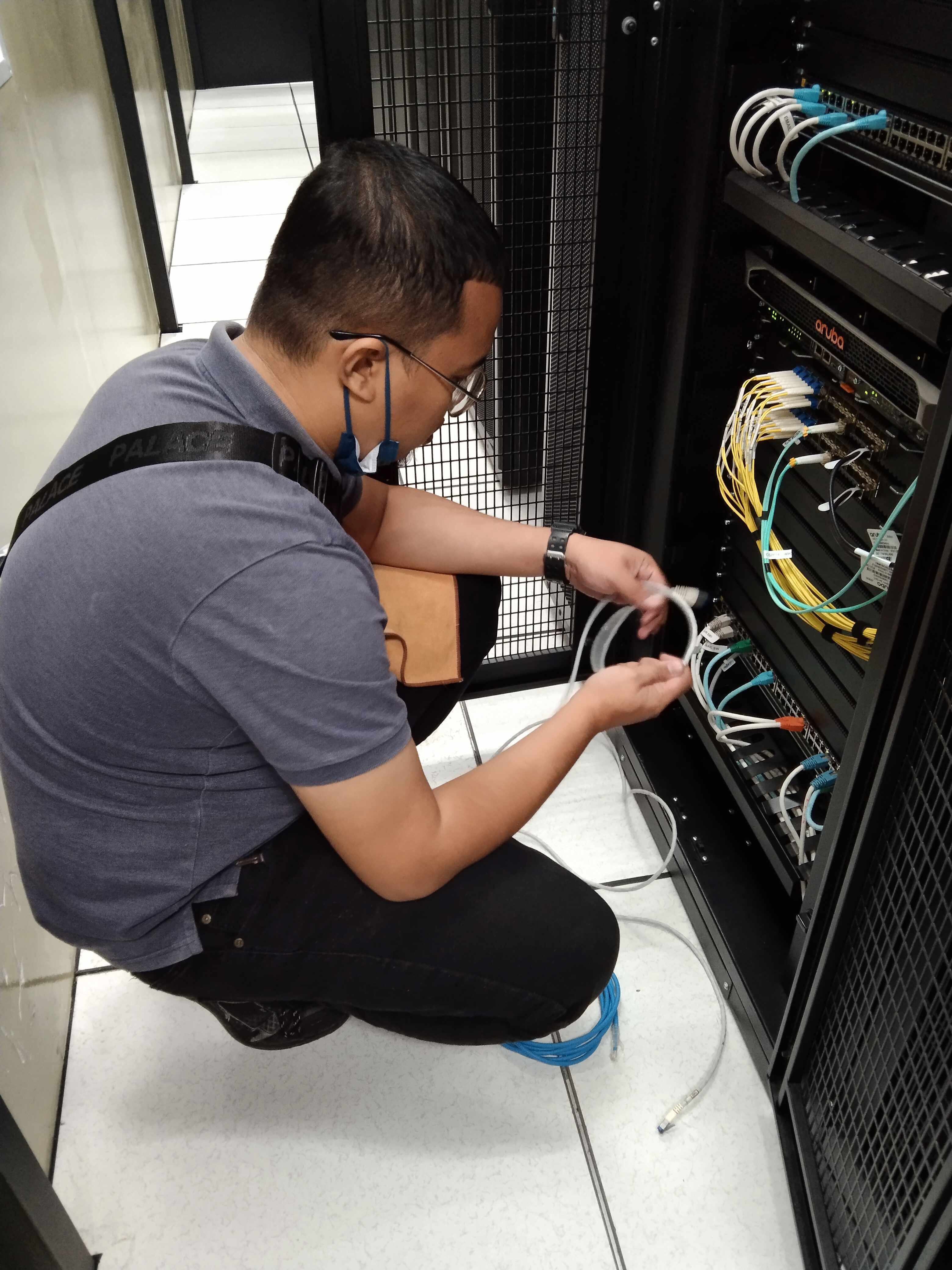 Technician performing fiber optic splicing, connecting multiple cables inside a distribution box